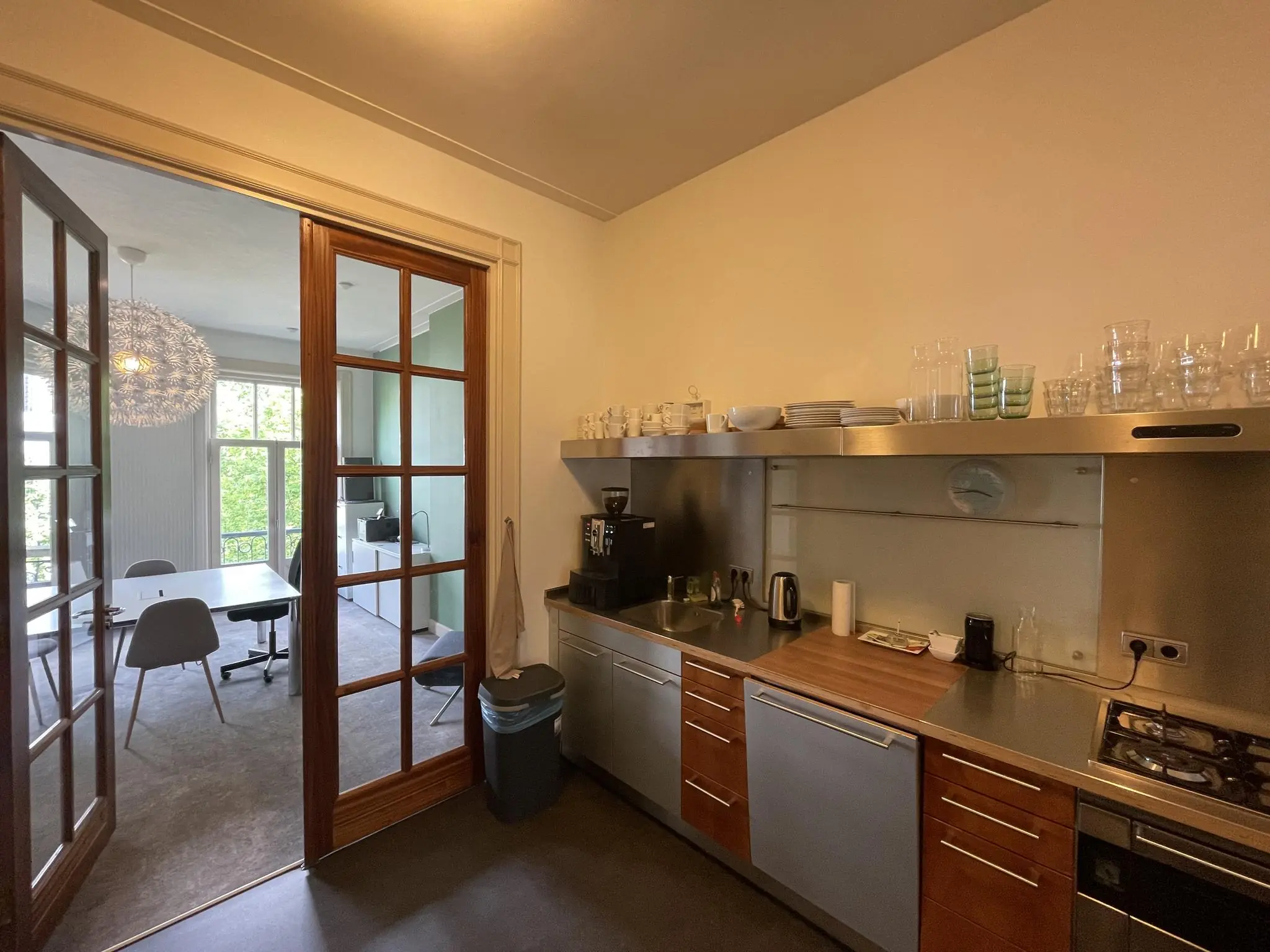 Moderne bedrijfskeuken met ingerichte kitchenette en uitzicht op een vergaderruimte aan de Oranje Nassaulaan.